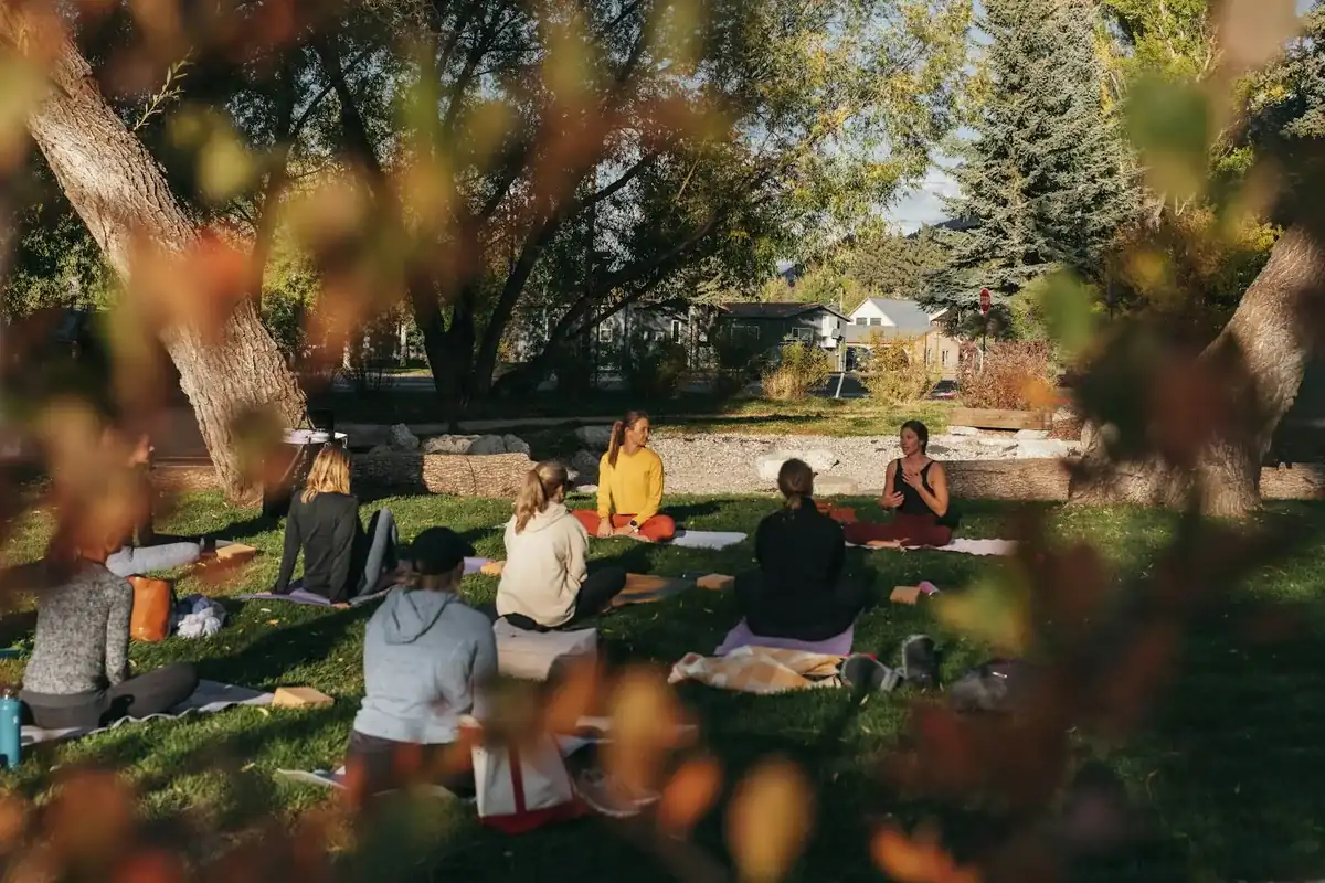 A circle of women sitting together outdoors in warm golden light, in quiet conversation